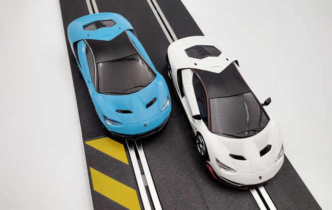 Two sleek Lamborghini racing side by side on Scalextric track.