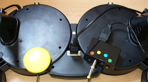 The underside of an adapted Playstation Rock Band drum kit including accessibility switch interface.