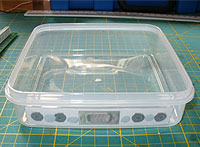 Tupperware box with drilling template blue-tacked into place.