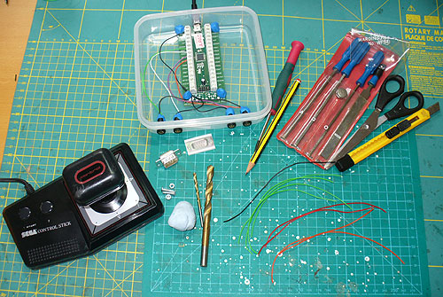 The basic parts needed from top left clockwise: 5g pouch of SUGRU rubber compound, switch sockets and wire, Ultimarc A-PAC PCB, Tupperware sandwich box, USB lead.